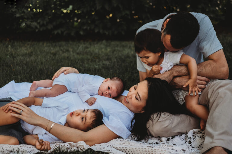 Best Maternity and Newborn Photographer Washington DC family of five with baby girl daughter toddler girl and young boy son laying on blanket outdoors